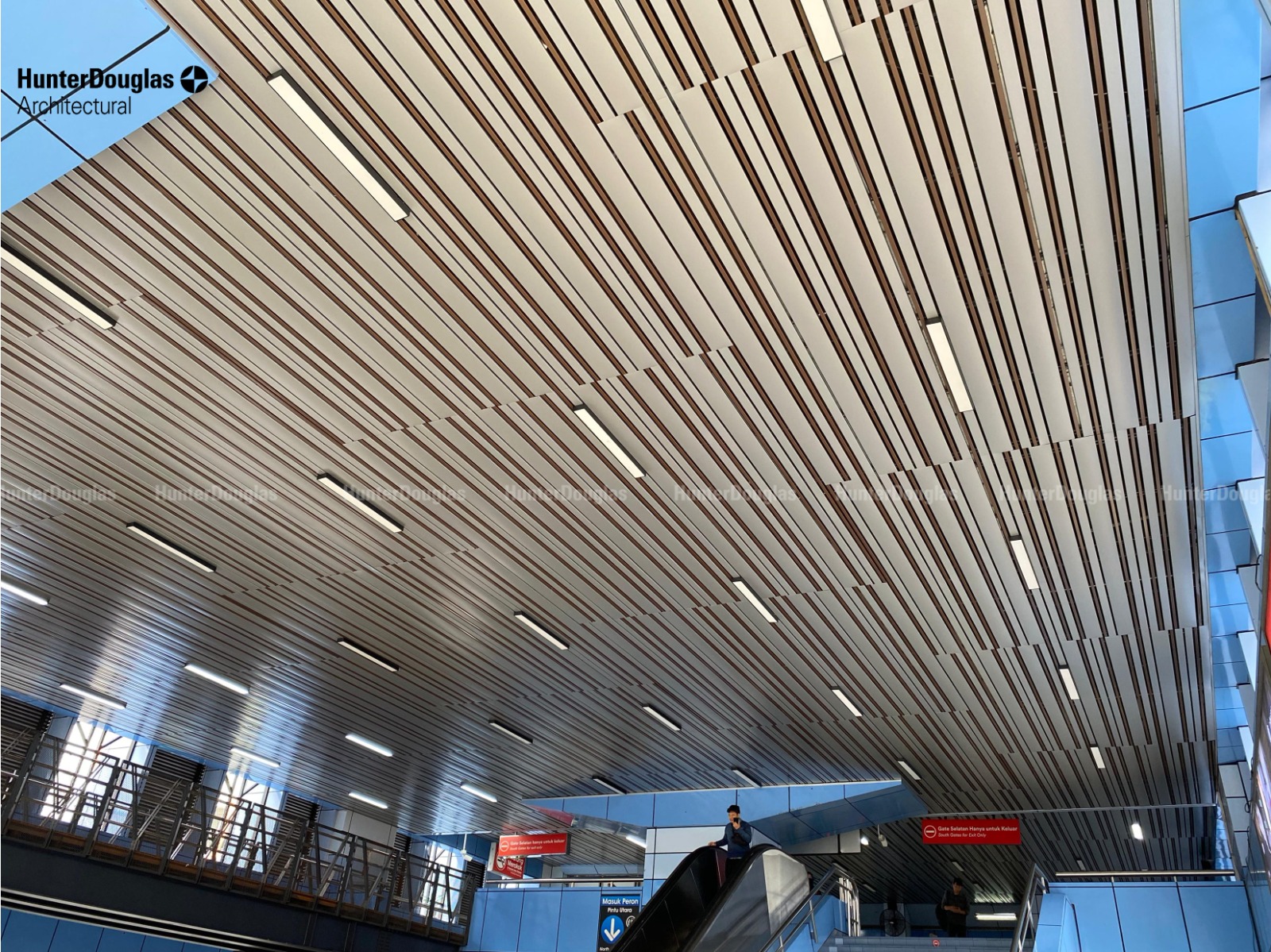 Large-scale ceiling execution with linear and baffle ceiling systems in an airport terminal.
